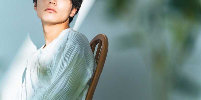 イスに座って気だるげな表情の若い男性の写真