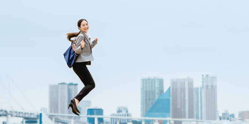 オフィス街を背に大きくジャンプする女性