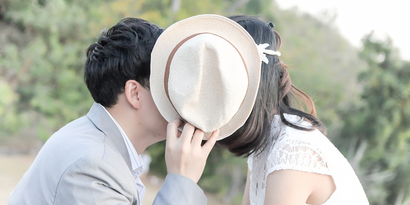 帽子で隠してキスをするカップル