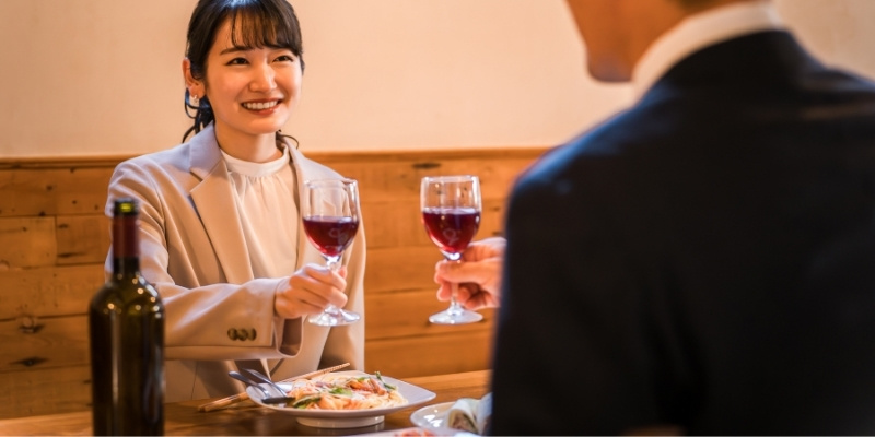 向かい合ってレストランで乾杯する男女