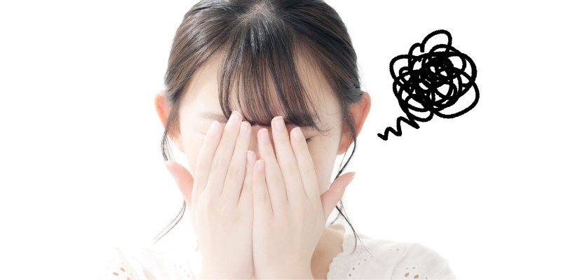 顔を覆う女性の写真。頭の横に黒いモヤモヤマークが描かれている