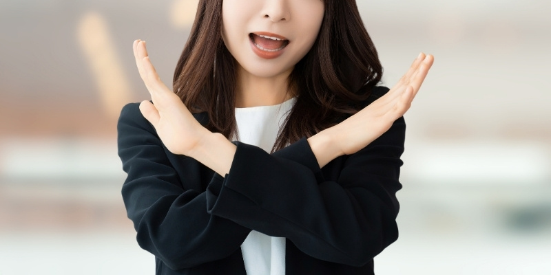 両手でバツマークをつくるビジネスウーマンの写真