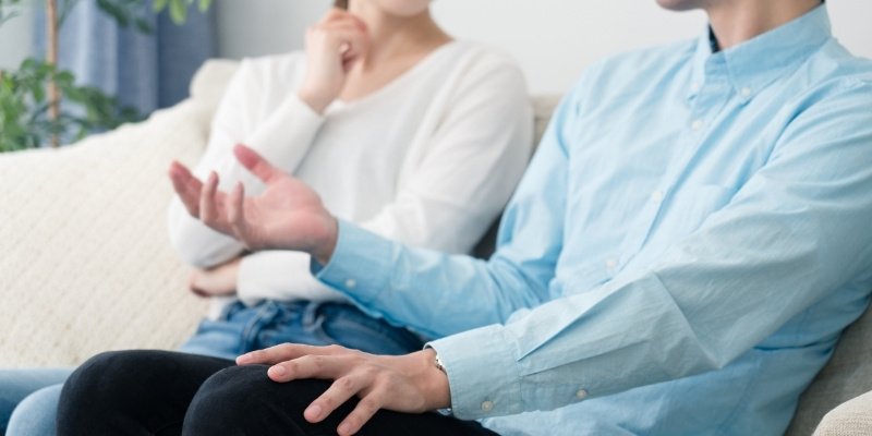 ソファに座って話すカップルの写真