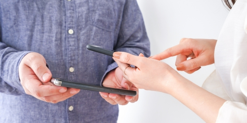 スマホで連絡先を好感している男女の写真