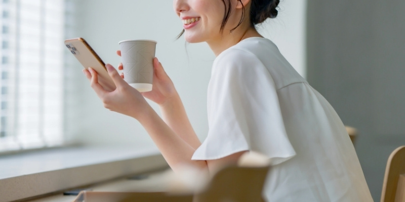 カフェでスマホを片手に微笑む女性の写真