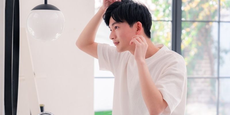 鏡の前で身だしなみを整える男性の写真