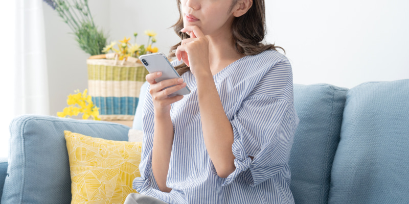 スマホを見て悩む女性