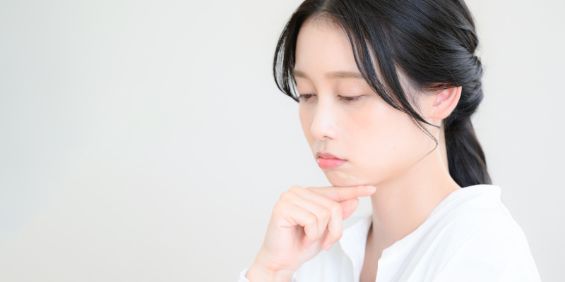 顎に手を当てて悩む女性の写真
