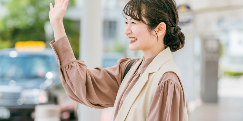 待ち合わせ中、相手を見つけてほほ笑む女性の写真