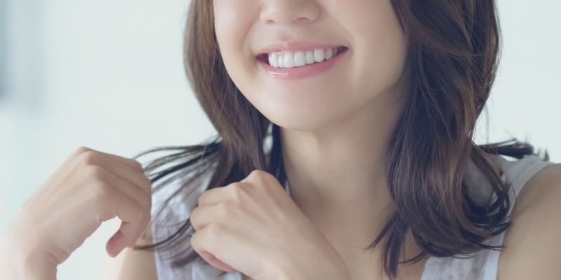 髪を触りながら笑顔を見せる女性の写真
