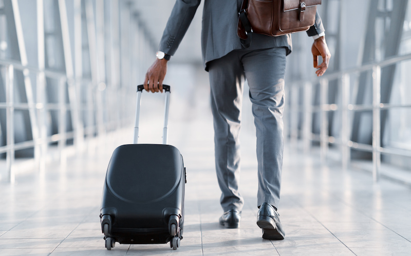スーツケースを引いて歩いている人の後ろ姿の写真