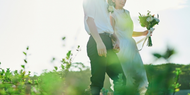 ブーケを持った新婦と手をつなぐ新郎の写真