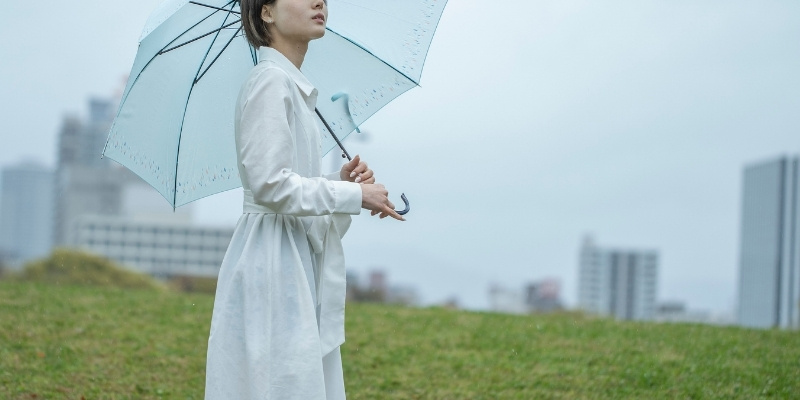 雨の中空を見上げる女性の写真