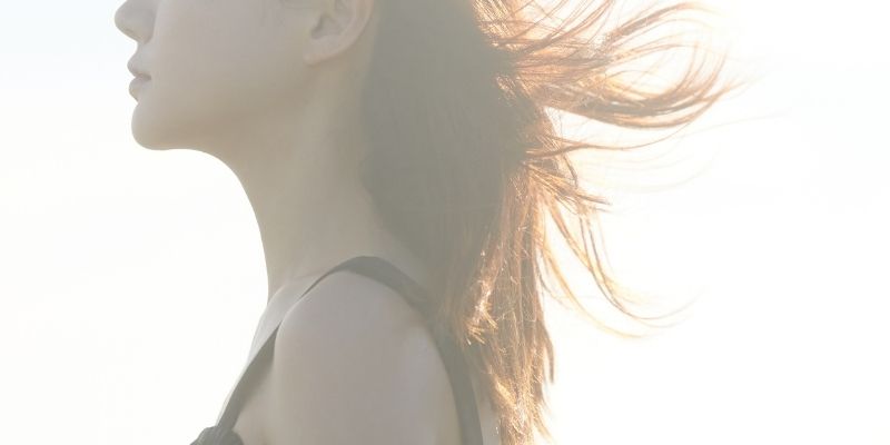アンニュイな表情でたたずむ女性の横顔の写真