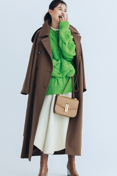 ブラウンのPコートに白スカートとグリーンのニットを合わせたモデル写真
