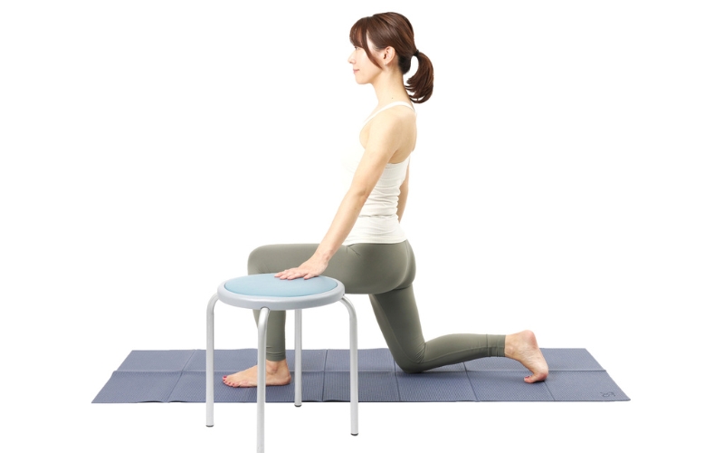 椅子で体を支えて膝立ちする女性