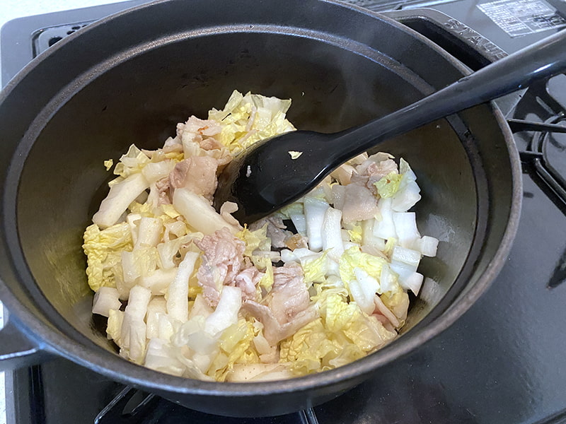 鍋で白菜と豚バラを炒めている工程写真