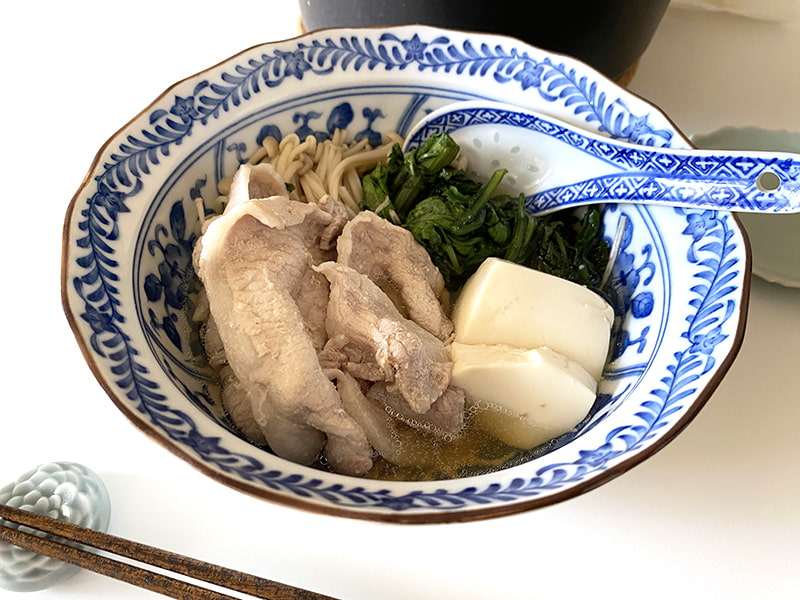 小皿に取り分けられた豚肉、春菊、豆腐、えのきとレンゲ