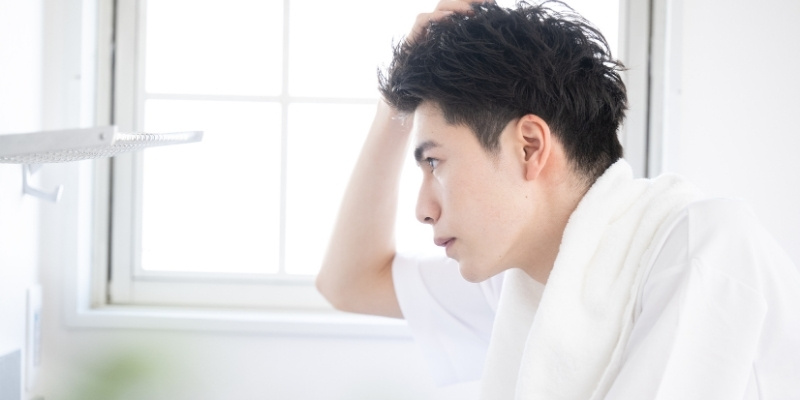 鏡の前で髪を整える男性の写真