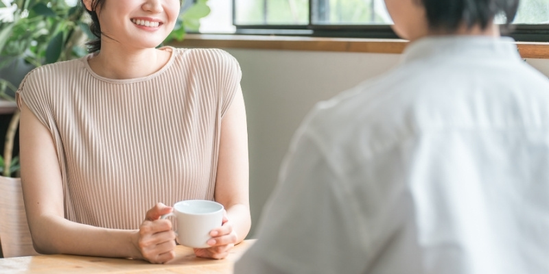 カフェで笑顔で会話する男女の写真