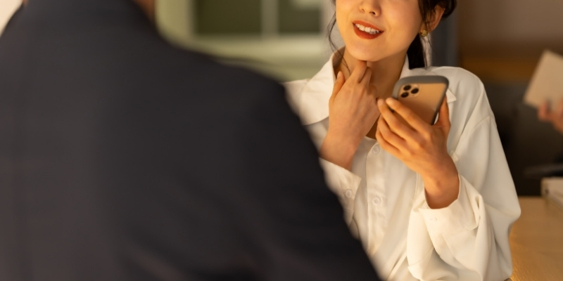 スマホを片手に男性と笑顔で話す女性の写真
