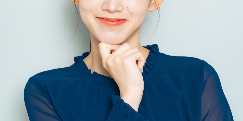 考えるポーズをとった笑顔の女性の写真