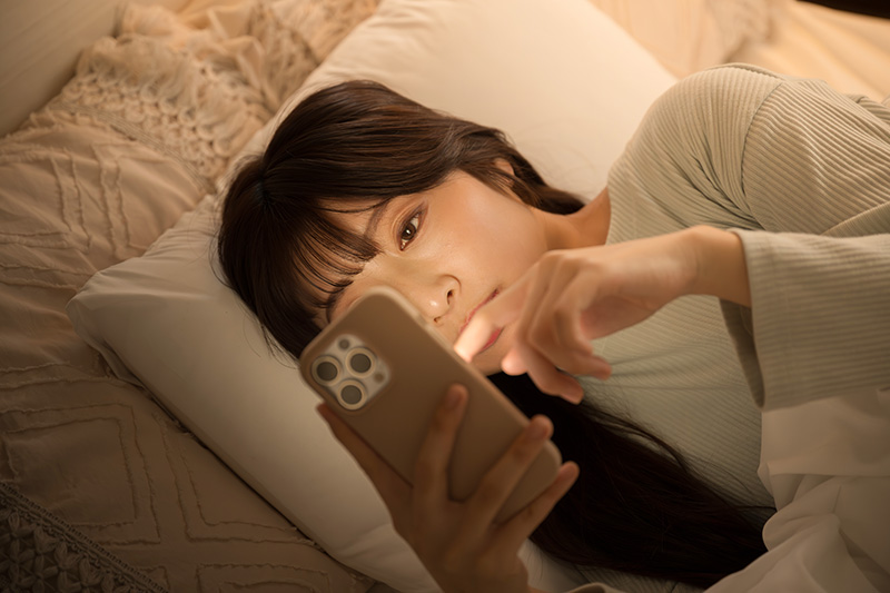 夜中にスマホを見る女性