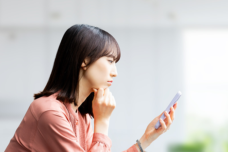 スマホを見て考える女性