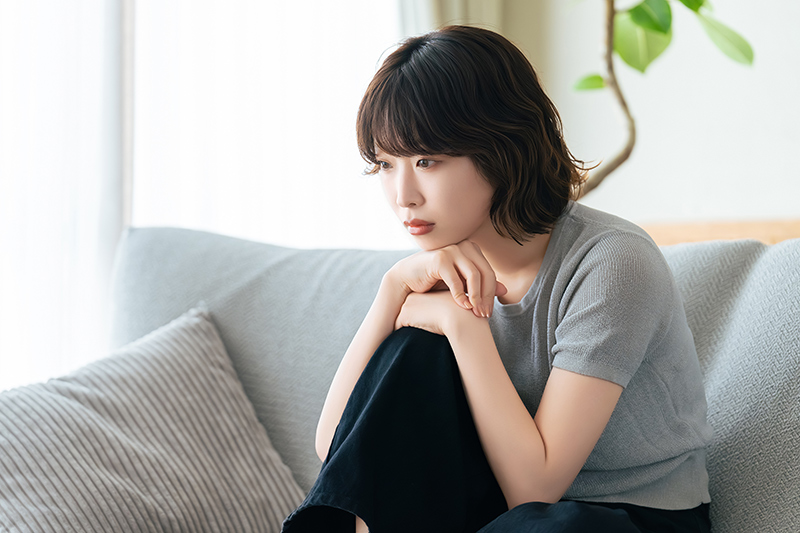 ソファに座って考えごとをする女性 