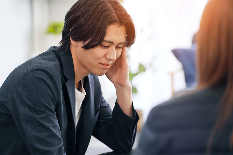 視線をそらして会話をする男性