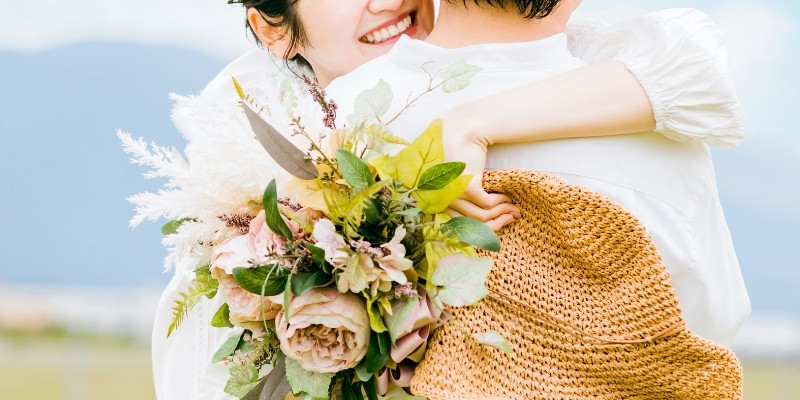ブーケを持つ女性が男性に抱き着いている写真