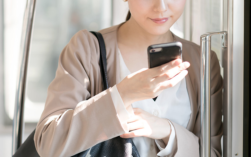 電車でスマホを眺める女性