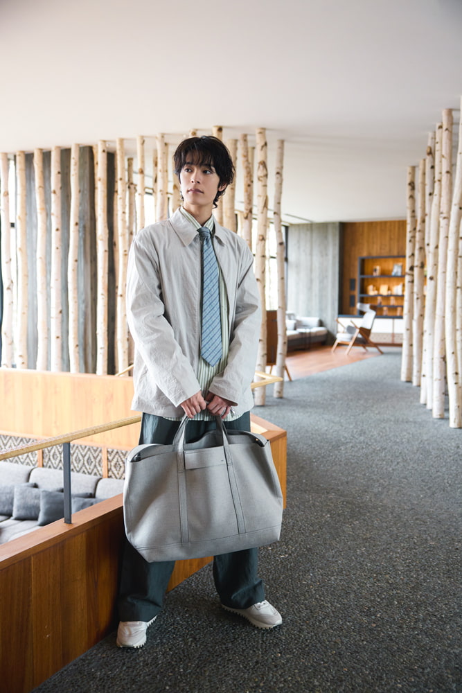 バッグを持って立つ塩野瑛久さん