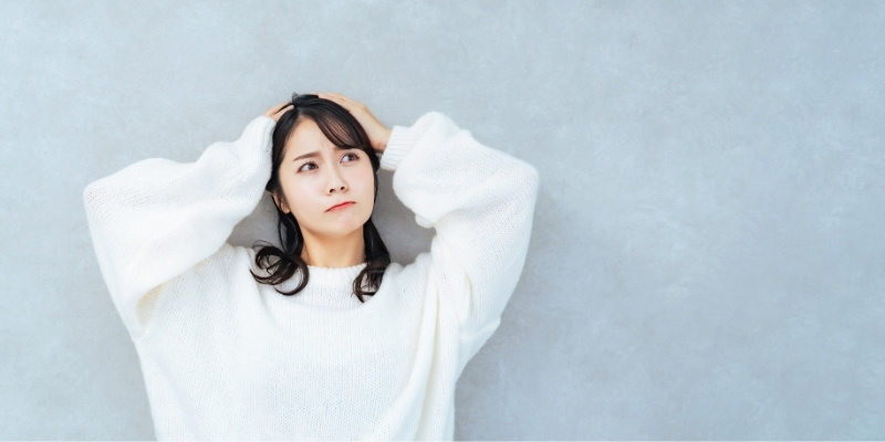 頭を抱えて悩む女性の写真