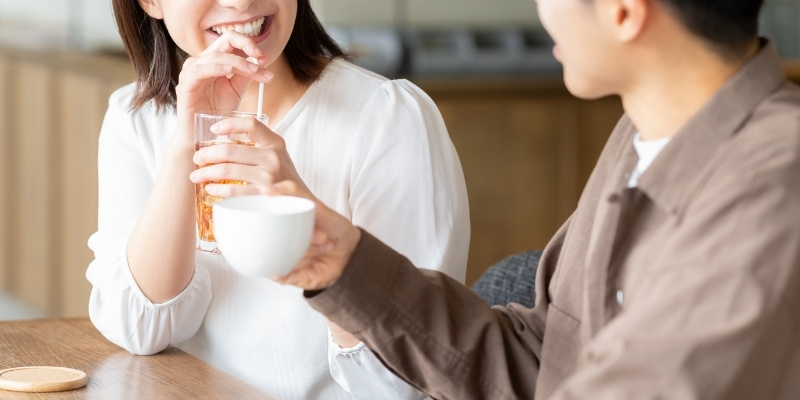 カフェで横並びに座り、楽しそうに会話する男女の写真