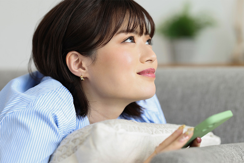 スマホを見ながら考えごとをする女性