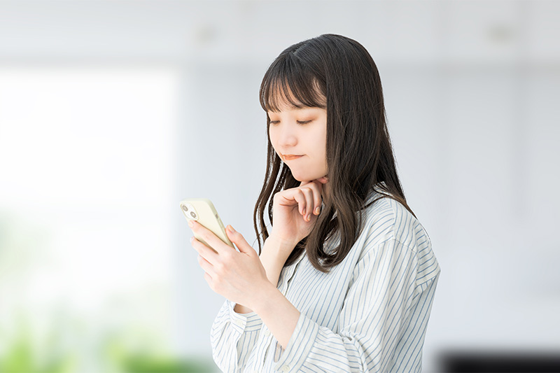 スマホを見ながら考える女性