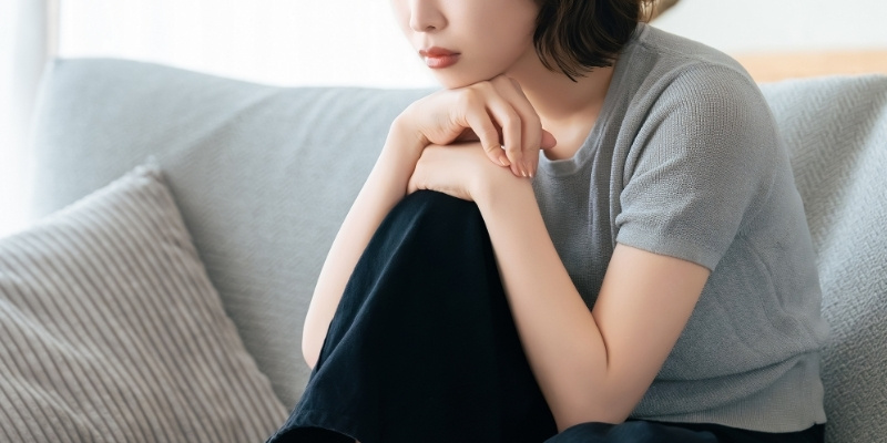 ソファに座って考え込む女性の写真