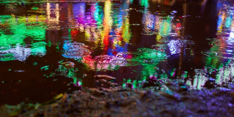 夜の雨に反射したイルミネーションの写真