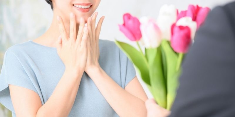 チューリップの花束を男性に渡され、喜ぶ女性の写真