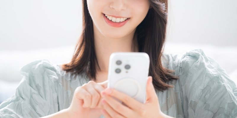 スマホを見てほほ笑む女性の写真