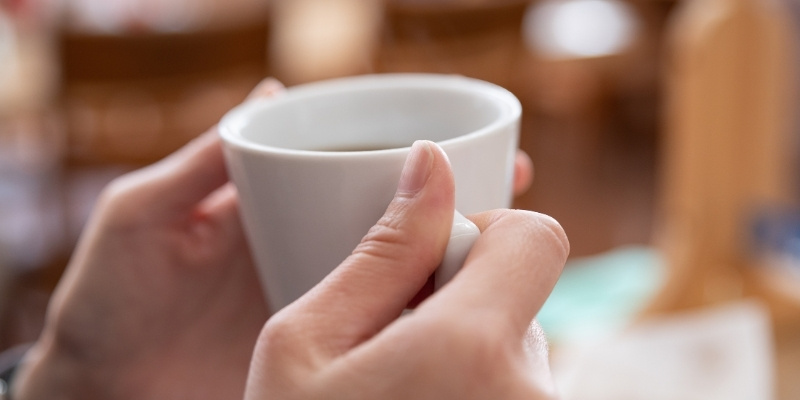 コーヒーカップを持つ手元の写真