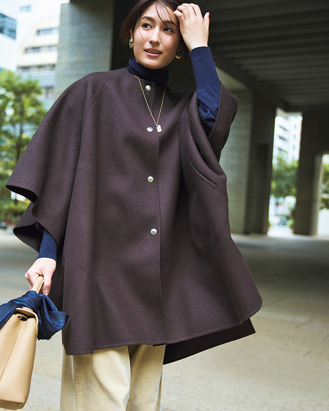 紫っぽいブラウンのケープポンチョ×ネイビーニット×ベージュパンツコーデ