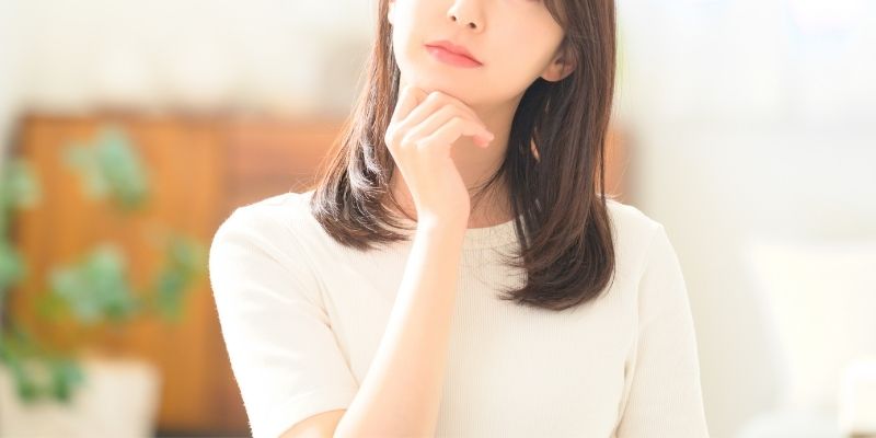 顔を見上げ、顎に片手を添えて考え中の女性の写真