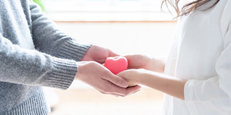 ハートのモチーフに手を添えている男女の写真