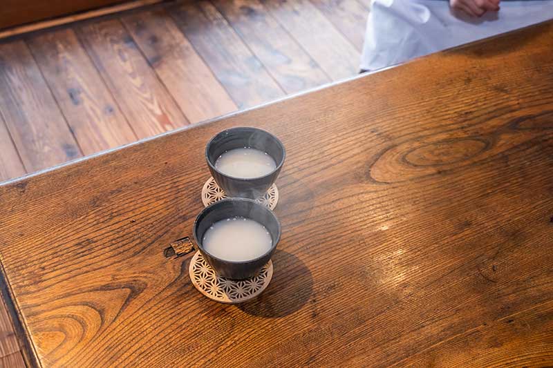 湯呑みに注がれた甘酒がふたつ、テーブルの上に置かれている