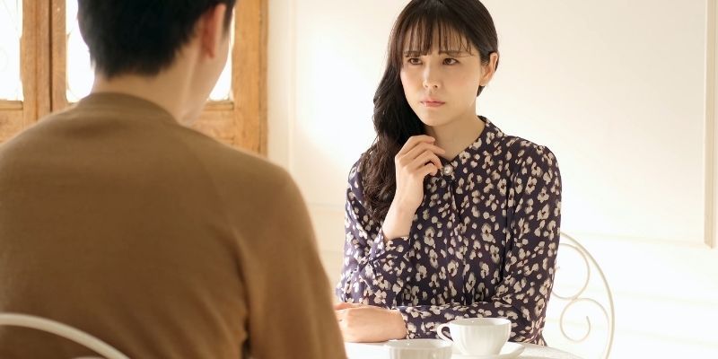 カフェにて険しい表情で男性を見つめる女性の写真