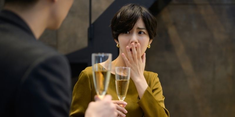 バーで男性に何か言われて「ありえない」というジェスチャーをする女性の写真