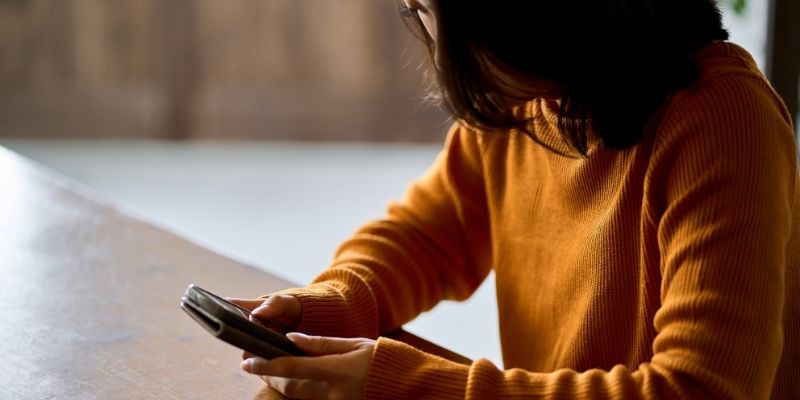 スマホを見てうつむく女性の写真