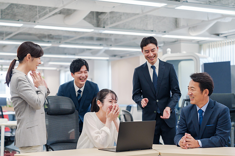 チームメンバーでにこやかに仕事をするオフィスワーカー